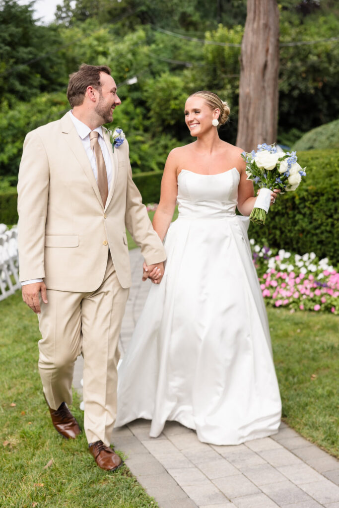 Quinn and Josh walking hand in hand through the gardens at Sea Cliff Manor.