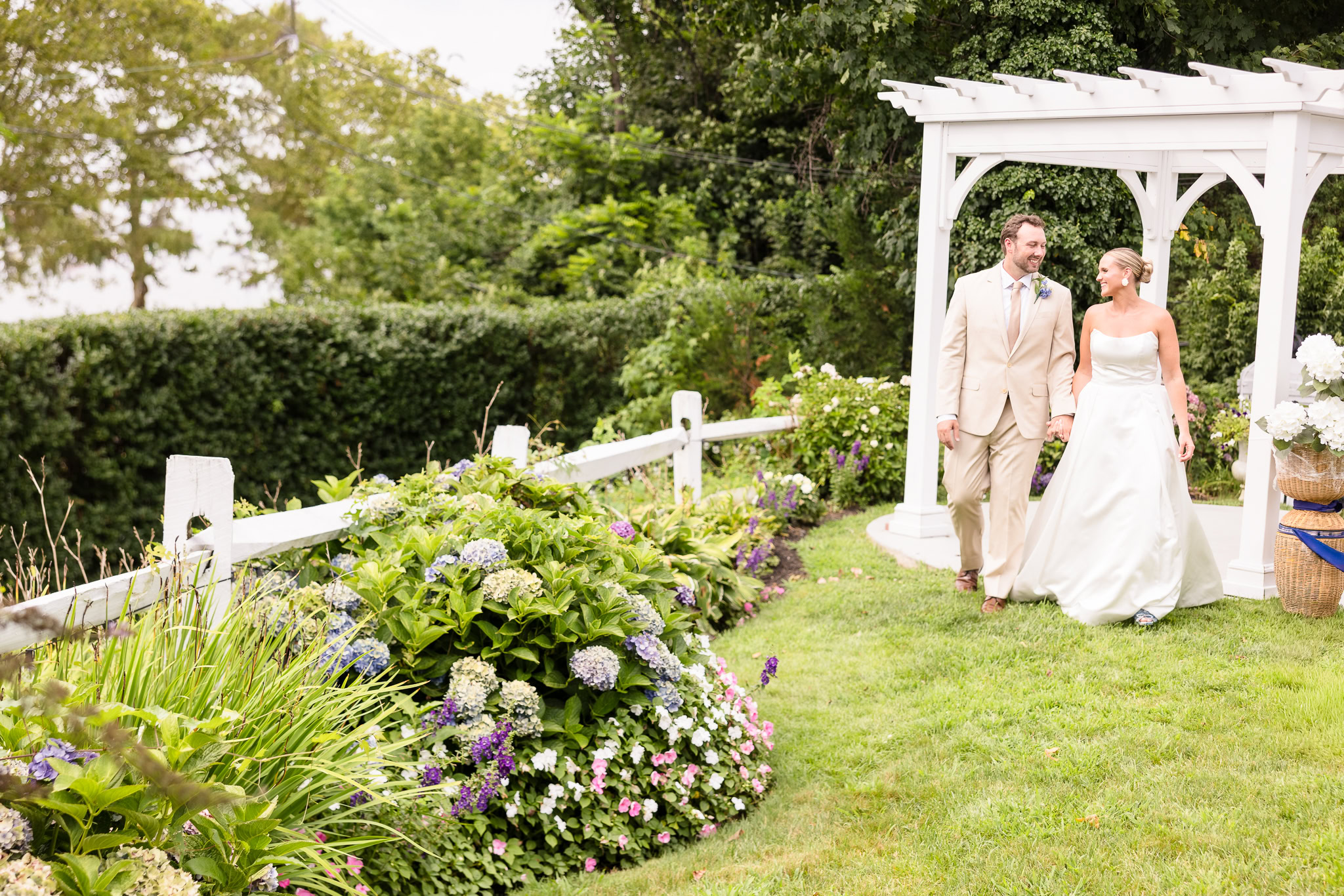 Quinn and Josh walking together beneath the white garden arbor at Sea Cliff Manor.