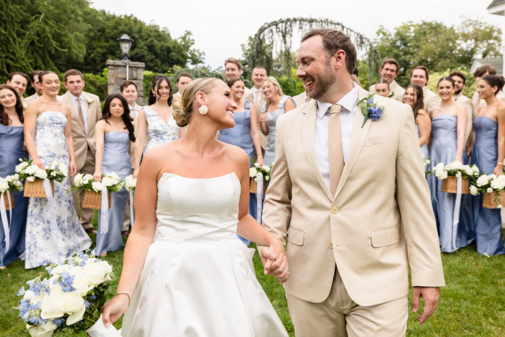 Quinn and Josh walk hand in hand in front of their large wedding party at Sea Cliff Manor.