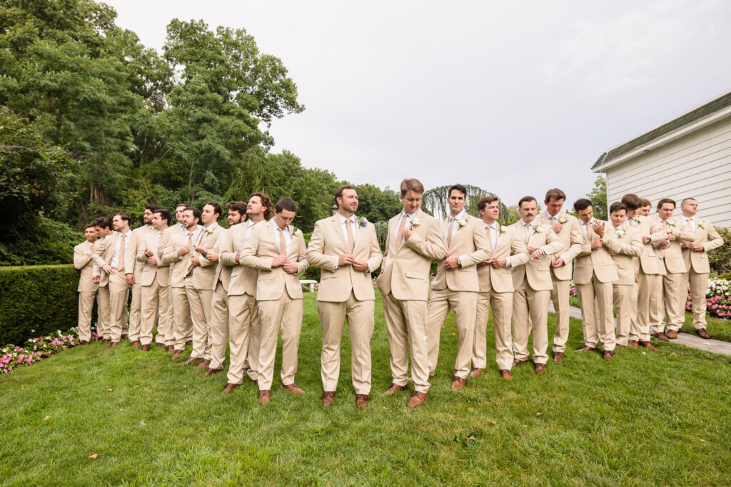 Josh and his groomsmen in tan suits gather on the lawn at Sea Cliff Manor.