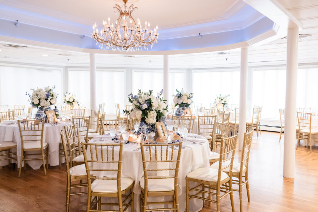 Sea Cliff Manor reception room decorated with blue and white florals, chinoiserie vessels, and gold chairs.