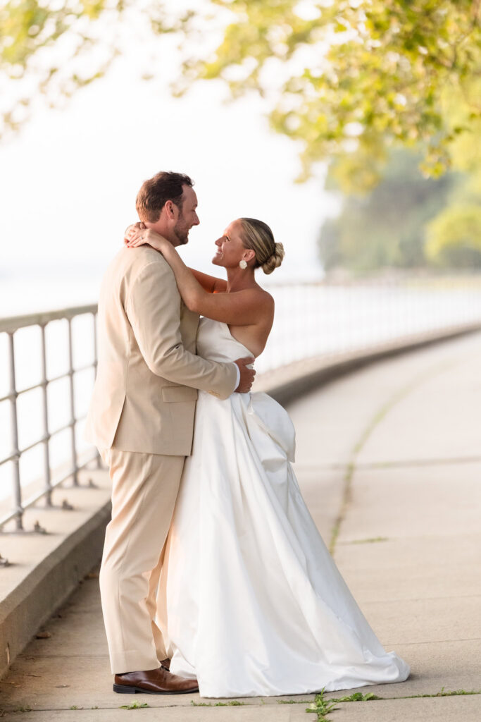 Quinn and Josh embrace beside the water during golden hour at their Long Island wedding.