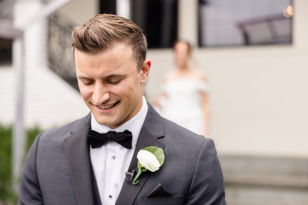 Groom smiling as he waits to see his bride during their first look at The Swan Club.