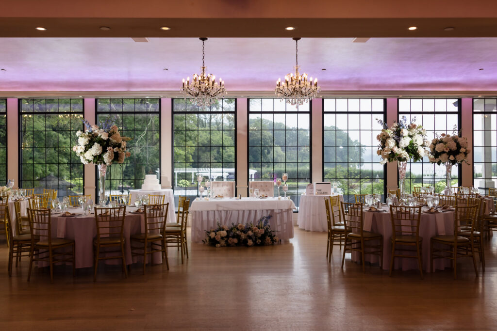 Elegant wedding reception at The Swan Club with waterfront windows, crystal chandeliers, and floral centerpieces