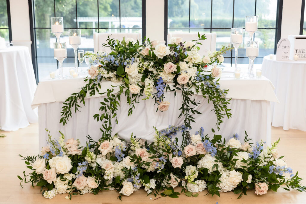 Sweetheart table decorated with white, blush, and blue flowers and candlelight at a Swan Club wedding
