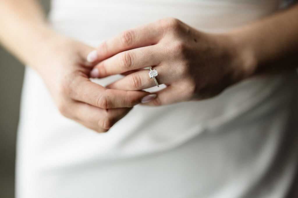 Close-up of the bride’s diamond engagement ring on her hand during wedding-day preparations.