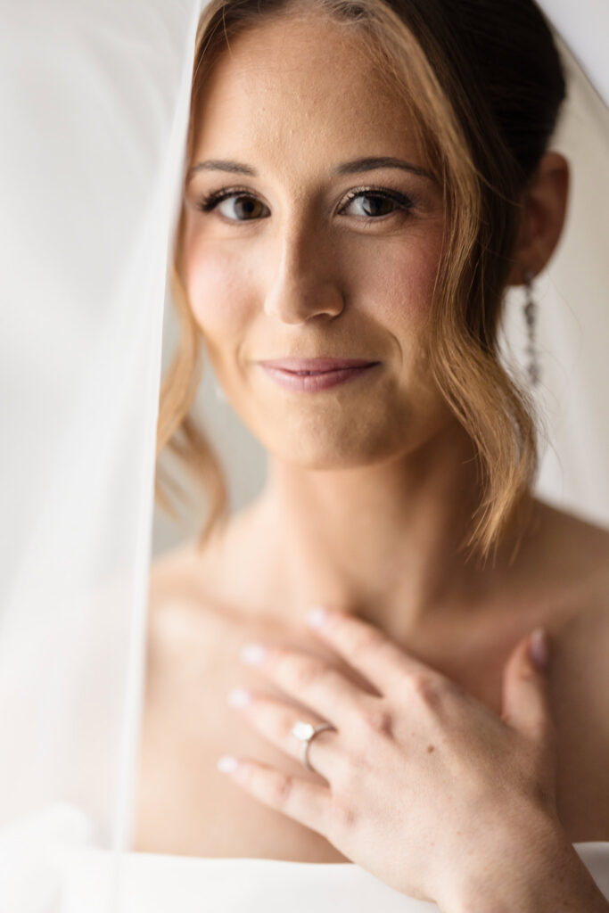 Close-up bridal portrait beside a softly lit window before the wedding ceremony.