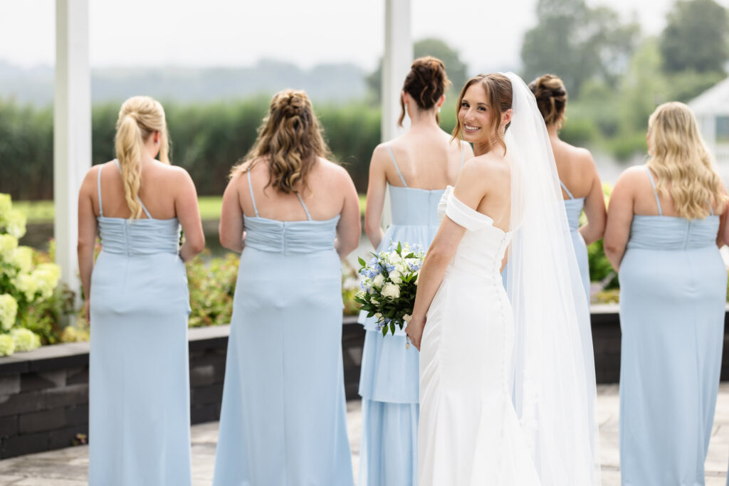 Tori looks back and smiles while posing with her bridesmaids outside at The Swan Club.
