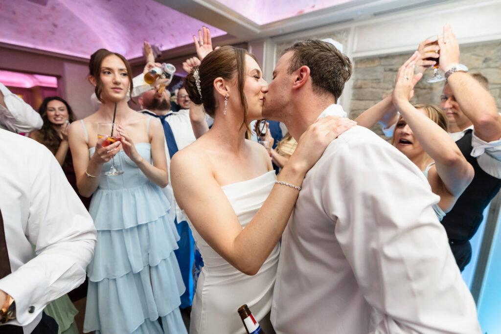 Tori and Mark kiss on the dance floor surrounded by friends and family at their Swan Club wedding reception.