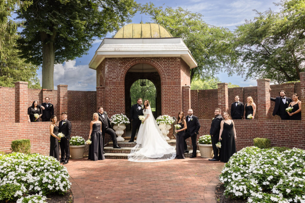 Wedding party arranged along the brick garden walls and steps surrounding the bride and groom at The Mansion at Woodside.